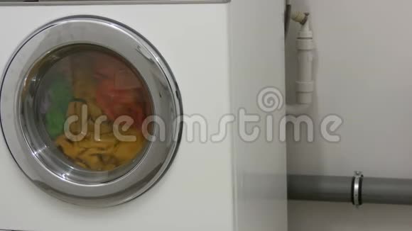 多种颜色的衣服洗衣在洗衣房的白色洗衣机里洗视频的预览图