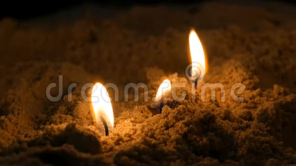 长长的薄薄的黄色教堂蜡烛在沙滩上燃烧视频的预览图