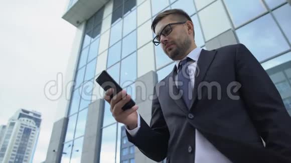 商人在户外使用手机检查信使通讯应用视频的预览图