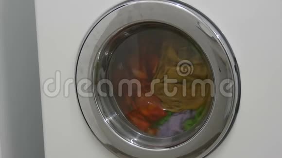多种颜色的衣服洗衣在洗衣房的白色洗衣机里洗视频的预览图