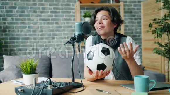 快乐的孩子录制关于足球的声音拿着球在麦克风里说话视频的预览图