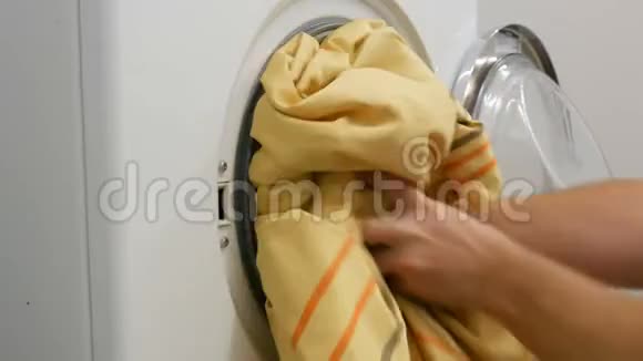 男用手将洗好的衣服装入洗衣机并将胶囊放入洗衣粉中视频的预览图
