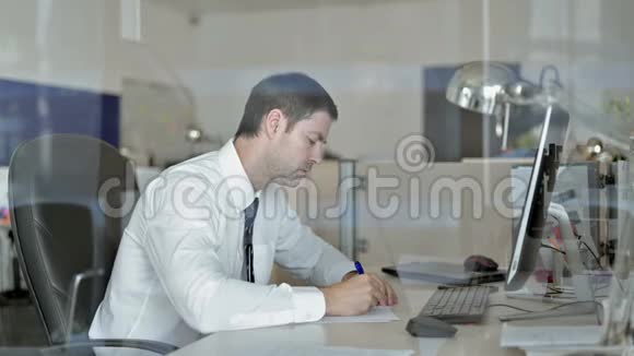 雄心勃勃的中年商人在办公室桌上写商务文件视频的预览图