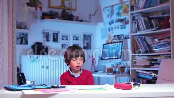 男孩坐在桌子旁举起手准备把学校的作业告诉他视频的预览图
