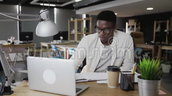 非洲青年在办公室集中写作和使用笔记本电脑视频的预览图