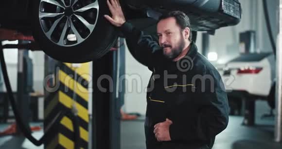 一个快乐而微笑的成熟的机械师在镜头前的一幅汽车服务肖像中站着时表现出一种巨大的喜欢视频的预览图