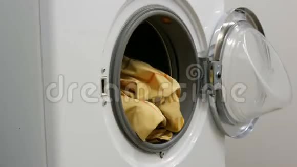 男性手将洗过的彩色衣服装入洗衣机并放置一个带有洗衣粉的胶囊加速视频的预览图