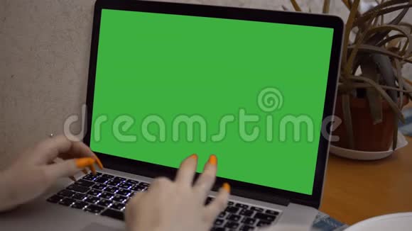 带有绿色屏幕的笔记本电脑女人在电脑上打钥匙绿色模拟笔记本视频的预览图