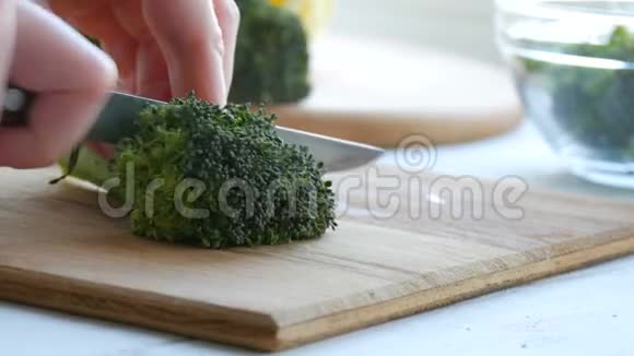 女性用刀子切出新鲜的绿色西兰花甘蓝放在厨房的木板上用刀煮切菜素食视频的预览图