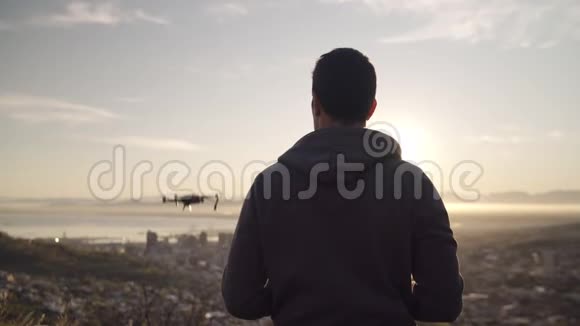 在阳光明媚的户外阳光明媚的一天一名男子在日出时驾驶无人机飞过一座城市的替罪羊未来主义视频的预览图