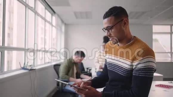 技术娴熟的年轻非洲商人正和同事一起在办公室里看着手持数码平板电脑的相机视频的预览图