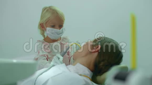 女孩把唾液喷射器放进医生的嘴里视频的预览图