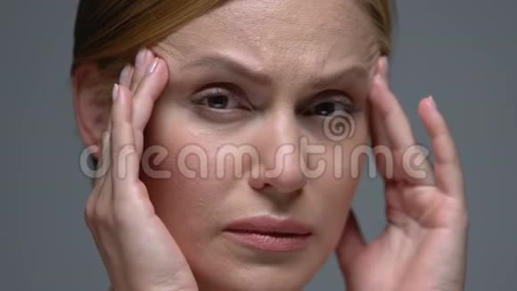 心烦意乱的女人按摩太阳穴看镜头偏头痛头痛视频的预览图
