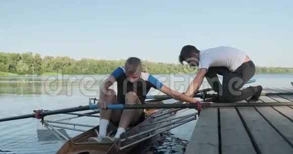 男孩15岁16岁划船运动皮艇少年们从船上下来折桨视频的预览图