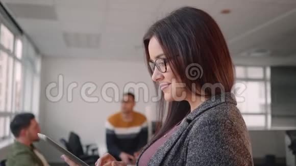 一位自信微笑的年轻女商人与她的商业团队一起使用电脑笔记本电脑的肖像视频的预览图
