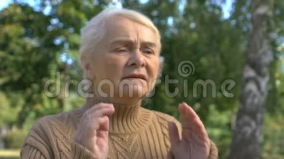 老年女性头痛在户外按摩太阳穴偏头痛症状视频的预览图