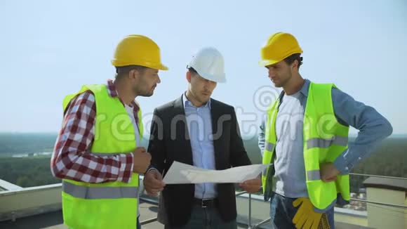 年轻的男老板带着安全帽和工人讨论施工计划视频的预览图