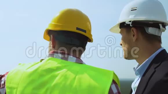 承包商和男性客户头盔讨论未来的建筑位置屋顶视频的预览图