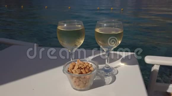 两杯白葡萄酒放在海边的桌子上视频的预览图