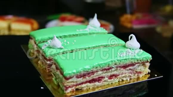 特写三个绿色釉面分层蛋糕片在黑架子上旋转视频的预览图