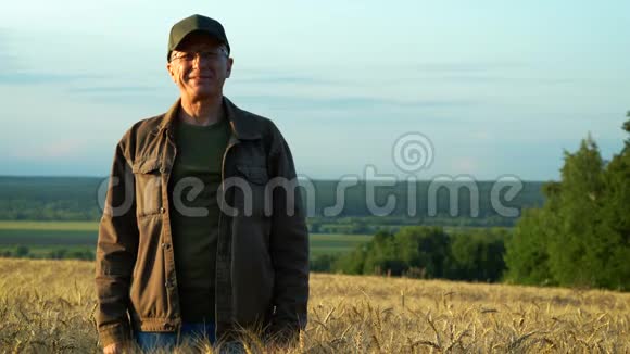 一个快乐的中年男人微笑着站在麦田上在一个夏天欣赏着他周围的大自然视频的预览图