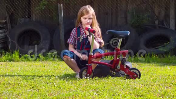 穿工作服的女孩在院子里修理自行车视频的预览图