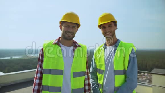 戴着安全帽和夹克的专业施工人员微笑着拍照视频的预览图