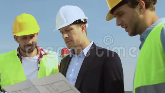 男建筑师西装革履戴安全帽与建筑工人讨论房屋方案视频的预览图
