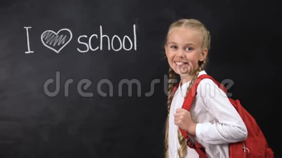 我爱学校写在黑板上可爱的女孩站在旁边小学教育视频的预览图