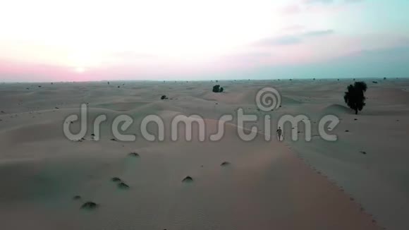 日落时一个人沿着沙漠中的沙丘奔跑无人机射击视频的预览图
