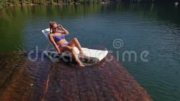 女人躺在太阳床上戴着太阳镜和泳衣女孩在洪水木水下码头休息路面是视频的预览图