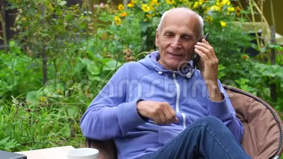 退休老人打电话在户外慢动作喝茶视频的预览图