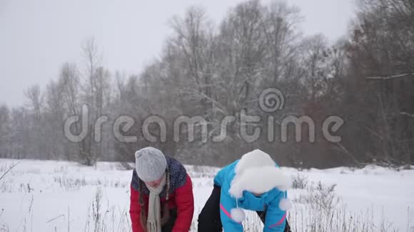 家庭在冬季公园玩圣诞假期慢动作快乐的母女把雪吐了雪落了视频的预览图