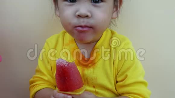 一个快乐微笑的亚洲女孩的肖像喜欢在户外吃冰淇淋视频的预览图