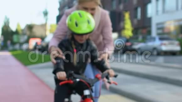 母亲支持女儿学习骑自行车家庭照顾关系视频的预览图