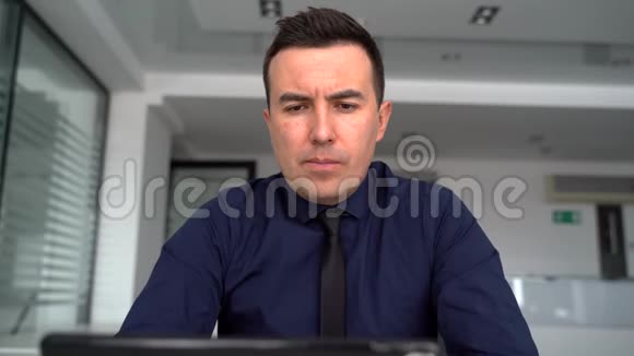 一个深思熟虑的人正在一台笔记本电脑上工作并通过视频链接交谈视频的预览图