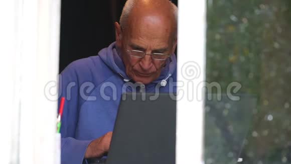 老人在窗台上用灰色笔记本电脑慢动作视频的预览图