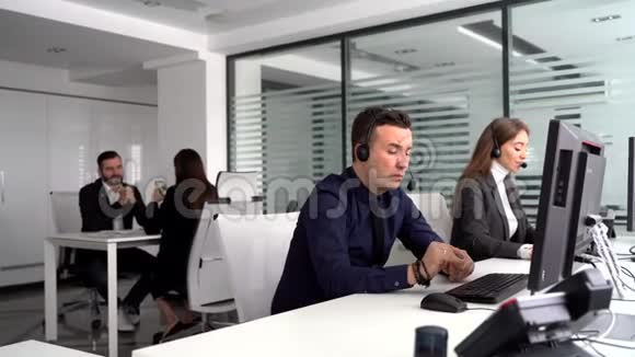 呼叫中心的员工服务客户在同事的背景下讨论一份合同视频的预览图