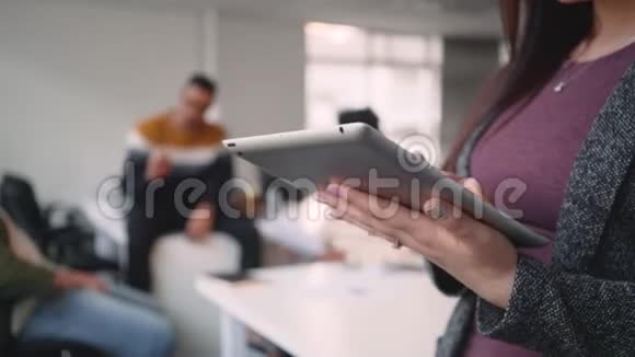 在办公室里同事在后台交流时女商人正在制作数码平板电脑视频的预览图