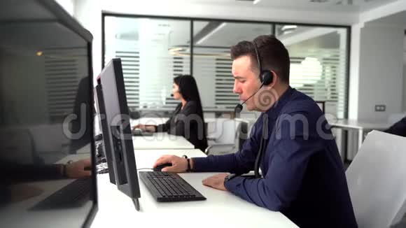 英俊的男性客户服务代理工作在呼叫中心办公室作为电话营销员视频的预览图