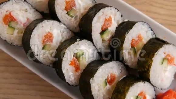 大寿司卷在诺里与鲑鱼蟹棒黄瓜费城奶酪附近有绿色的芥末和红色视频的预览图