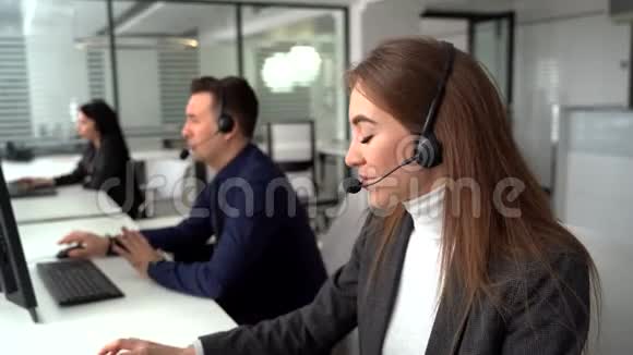 一位年轻漂亮的女商人和一位戴着耳机在办公室工作时使用笔记本电脑的漂亮商人视频的预览图