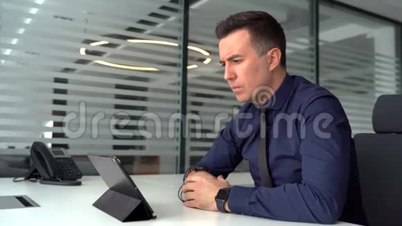 专注的年轻商人在现代化办公室的笔记本电脑上与客户进行视频通话视频的预览图
