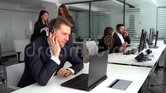 一个有魅力的年轻人和他的同事在呼叫中心工作视频的预览图