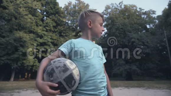 孤独沮丧的男孩在球场上拿着足球缺少朋友欺负问题视频的预览图