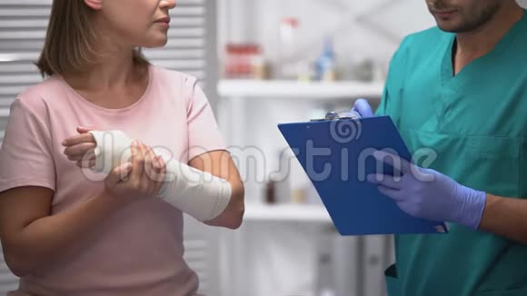 医生填写医疗文件检查女性手臂弹性包裹康复中心视频的预览图