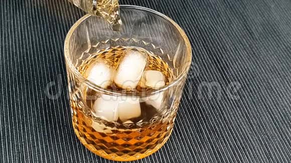 酒吧老板把威士忌倒在杯子里桌子上放冰块把注意力集中在冰块上威士忌在温暖的环境中放松时间视频的预览图