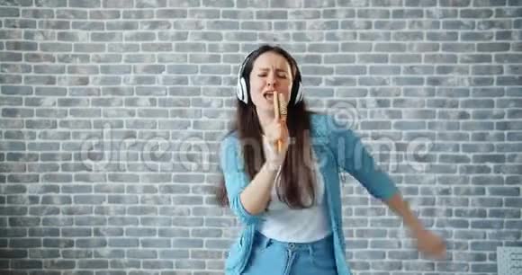 在砖墙背景下一位快乐的女士在梳子上唱歌视频的预览图