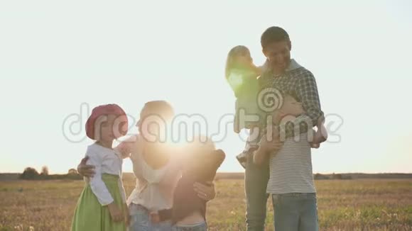 快乐的父母在夕阳的背景下亲吻他们的孩子大家庭视频的预览图