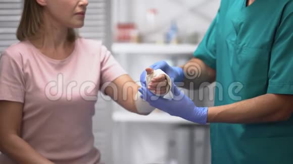 医生在女性患者手臂上固定弹性包裹创伤后康复视频的预览图